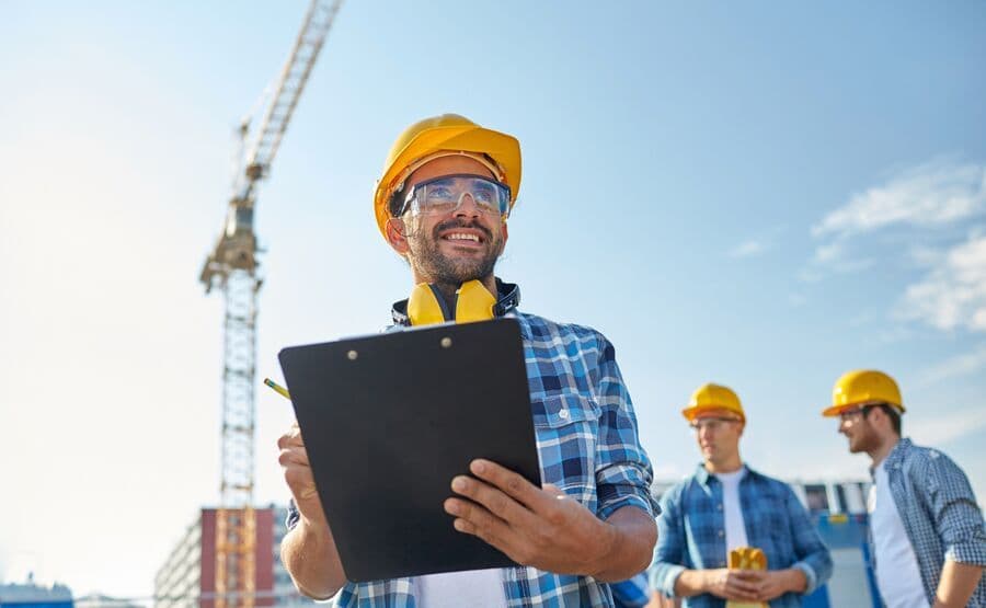Engenheiro sorridente em obra com prancheta